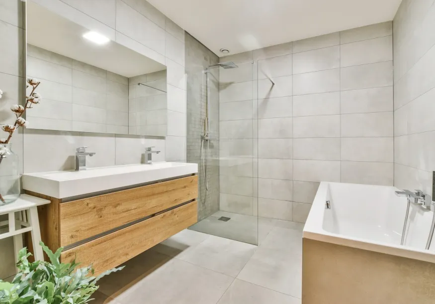 Helles Bad mit Doppelwaschtisch aus Holz, Glasdusche und Badewanne