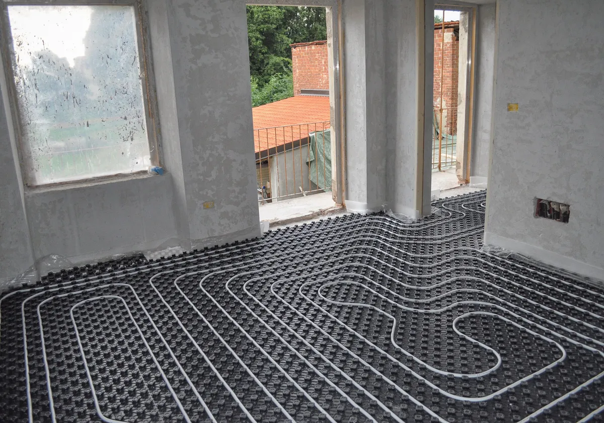 Verlegte Fußbodenheizungsrohre auf Noppenplatten in einem Rohbau